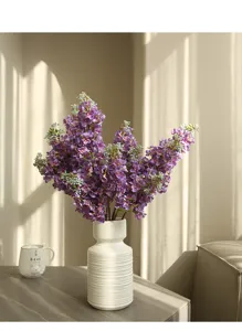 Artificial lilac flower bouquet detail, white ceramic vase home decor scene display.