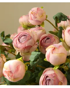Primo piano dettagliato di rose artificiali rosa, petagli delicati e foglie verdi realistiche.