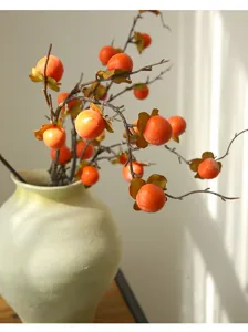 Nahaufnahme von künstlichen Persimonen Zweigen in einer Keramikvase für die Dekoration.