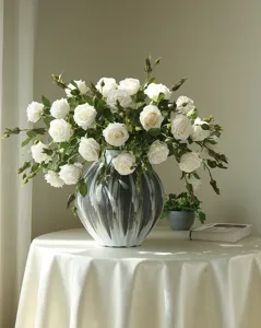 Detailed shot of artificial white rose bouquet in a stylish black and white ceramic vase.