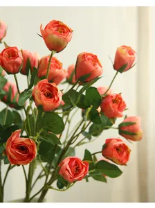 Vue détaillée de branches de roses artificielles orange avec des feuilles vertes.