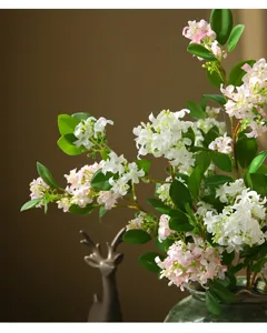Close-up detail of artificial orange jasmine flower branches with green leaves, home decor accent.