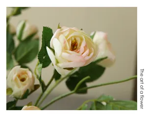 Gros plan de roses artificielles, fleurs en soie rose et blanche avec tiges vertes.