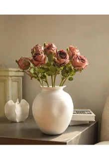 Detailed view of vintage artificial rose bouquet in white ceramic vase for decor.