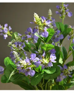 Vista detallada de una rama de flores artificiales moradas con hojas verdes brillantes.