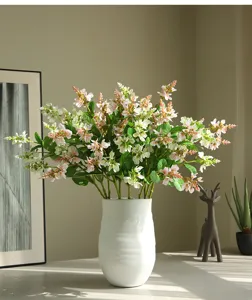 Flores artificiales de espuela en jarrón de cerámica blanca para decoración de hogar.