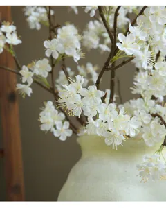 Detailed close-up of white artificial snow ball flowers in a pale green vase for home decor.