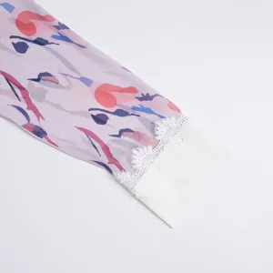 Detailed shot of women's long sleeve with abstract colorful print and white lace cuff trim.