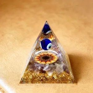 Crystal orgone pyramid detail showcasing evil eye bead and amethyst crystal chips inside resin.