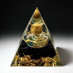 Resin orgone pyramid detail, showcasing crystal sphere, copper coil and tree of life design.