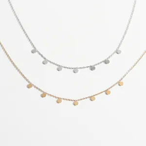 Nahaufnahme filigraner minimalistischer Münzanhänger Ketten in Silber und Gold Tönen.