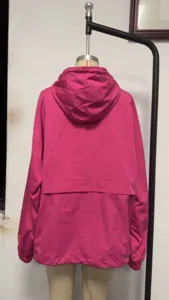 Detail view of women's solid color waterproof hooded windbreaker jacket with back windproof panel design.