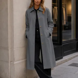 Vue détaillée du trench-coat gris pour femme avec revers et boutons et texture de tissu.