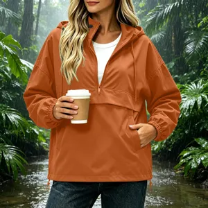 Detail view of women's orange hooded waterproof rain jacket in rainy forest setting.