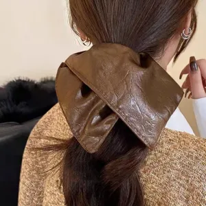 Vista detallada de coletero de pelo de cuero sintetico marron con elegante coleta de caballo
