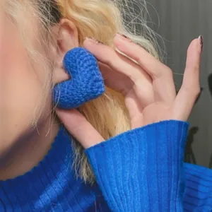 Gros plan de boucles d'oreilles cœur au crochet bleues, design en peluche tricotée mignonne.