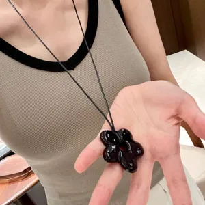 Close-up detail of black floral pendant necklace on dark cord, elegant daily accessory.