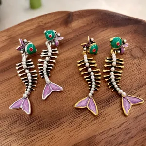 Vintage visgraat oorbellen met parels en groene koppen, detailweergave van de sieraden.