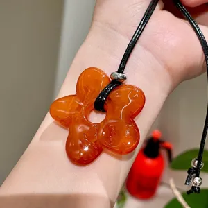 Close-up detail view of the orange translucent flower pendant necklace showing exquisite craftsmanship.
