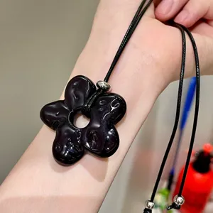 Detail view of a Korean-style simple black flower pendant long necklace, stylish sweater chain.