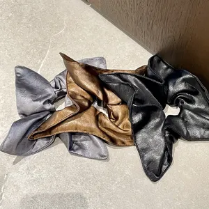 Primer plano de elegantes coleteros de piel sintética en gris, marrón y negro efecto arrugado.