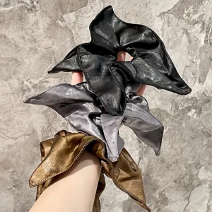 Detalle de coletero pañuelo de cuero, acabado metálico chic para coletas elegantes.