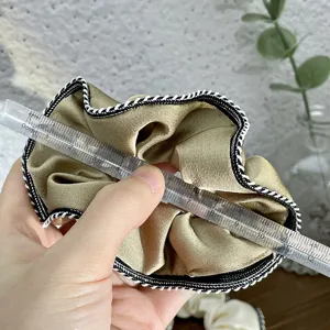 Detail view of satin hair scrunchie with black white edge, size measurement showcase.