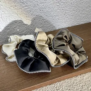 Detail view of retro french satin hair scrunchies with twisted braided edges, multi-color.