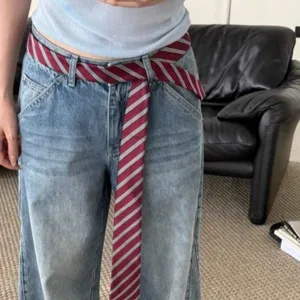 Vista detallada de elegante corbata a rayas usada como cinturón para un look casual.