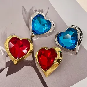 Vintage crystal heart earrings detail shot showcasing gold and silver metal luxury style jewelry.