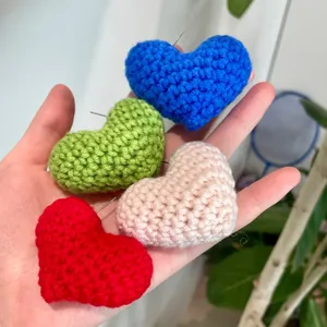 Détail de boucles d'oreilles cœur au crochet fait main, bijoux cœur en tricot coloré.