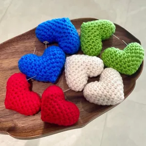 Gros plan de boucles d'oreilles coeur au crochet faites main avec des peluches colorées.
