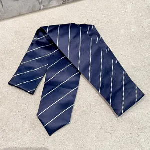 Vista detallada de una corbata estrecha azul marino elegante con rayas diagonales blancas.