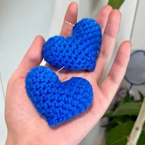 Gros plan de boucles d'oreilles cœur au crochet bleu, montrant texture et dimensions.