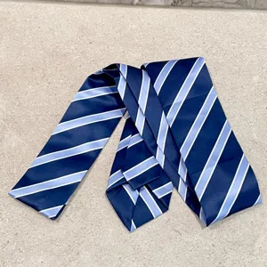 Detalle en primer plano de una corbata azul marino con rayas diagonales celestes.