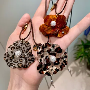 Detail view of unique resin flower pendant necklaces featuring pearl and leopard print.