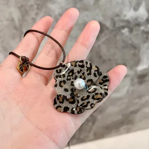 Leopard print flower pendant necklace with faux pearl center, delicate cord chain detail shot.