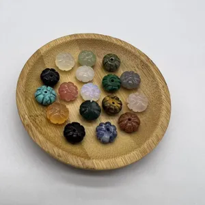 Close-up detail of mixed natural stone carved pumpkin beads on wooden tray for DIY jewelry.