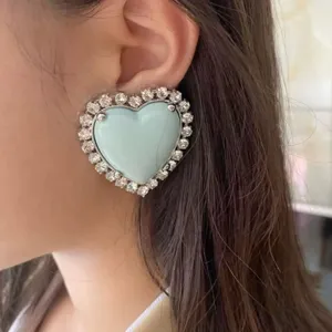 Gros plan detail des boucles doreilles coeur bleu clair aux strass cristal brillants.