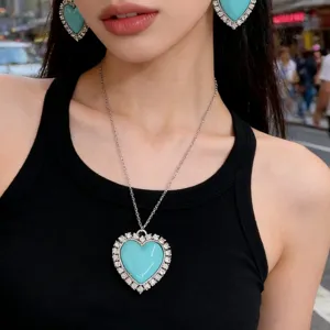 Vue en gros plan du collier et des boucles d'oreilles cœur en strass bleu étincelant.