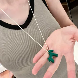 Detailed view of the green enamel horse pendant necklace with white cord, cute choker accessory.
