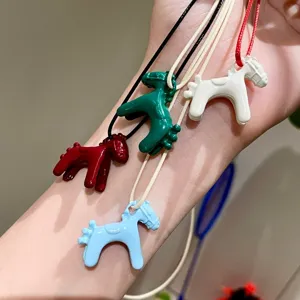 Colorful enamel horse pendant detail close-up view showing vibrant colors and smooth texture.