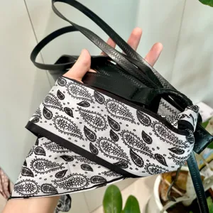 Gros plan détaillé d'une ceinture en cuir noir enveloppée d'un élégant foulard en soie paisley.