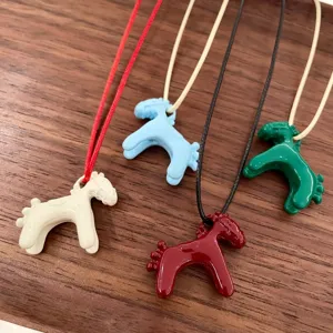 Close-up detail of colorful enamel 3D horse pendant necklaces in white, blue, red and green.