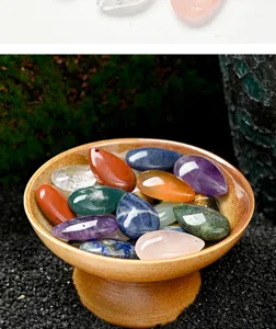 Primer plano detallado de colgantes de gema de cristal colorido en forma de gota en un bol.