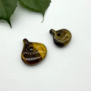 Natural tiger eye stone magatama pendant closeup, polished surface with chatoyant effect.