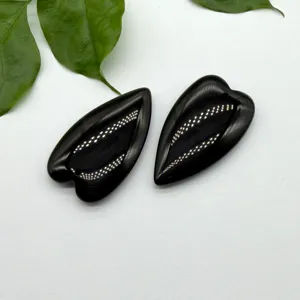Close-up detail of smooth black heart stone pendants, perfect DIY jewelry making component.
