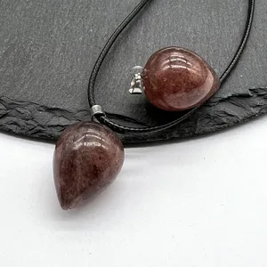 Close-up detail shot of drop-shaped crystal gemstone pendant with black cord necklace.