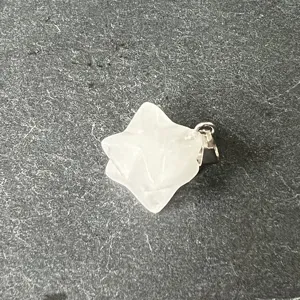 Nahaufnahme eines weißen Kristall Merkaba Stern Anhängers mit Metallöse auf Schiefergrund.