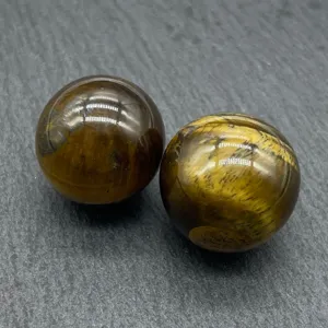 Close-up detail of polished 20mm natural tiger eye gemstone sphere showing cat eye effect.